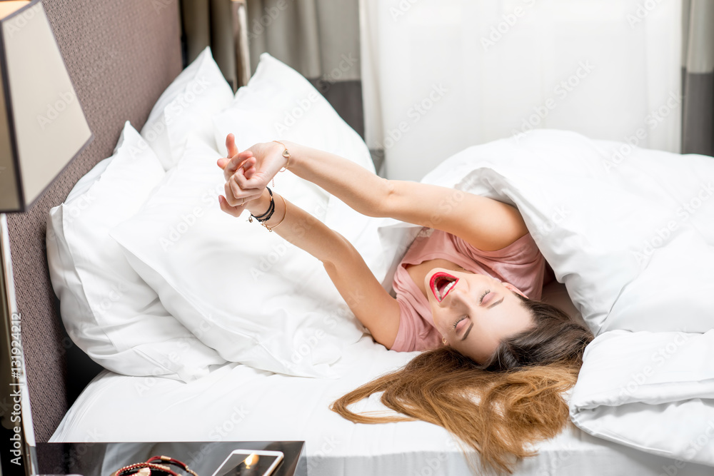 Beautiful young woman waking up in the bed at the morning. Good morning concept