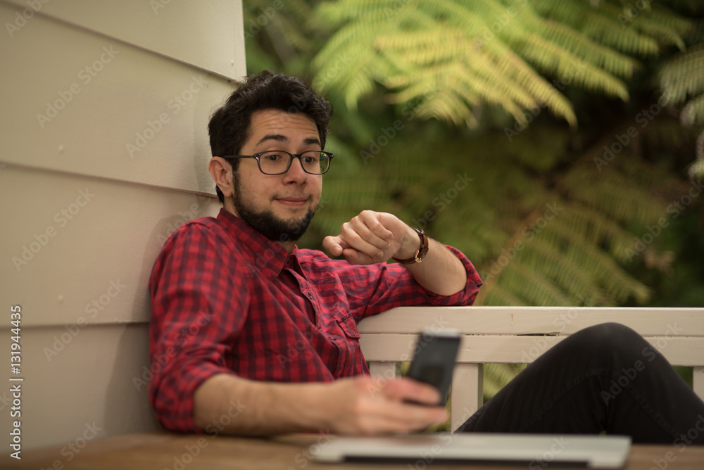 Young man with a laptop and smartphone sitting outdoor at home