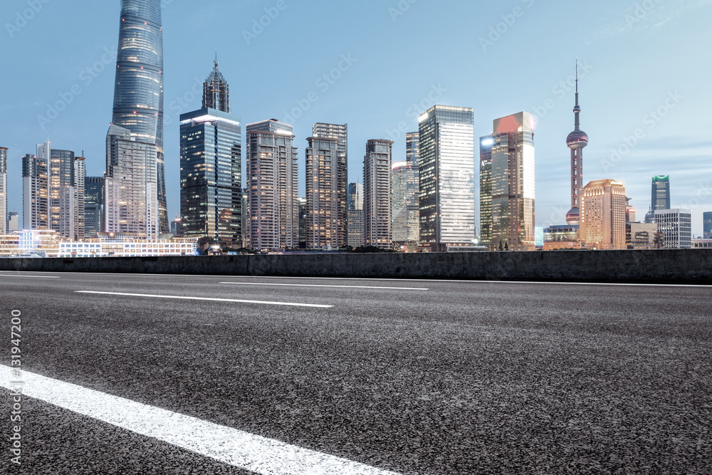 Asphalt road and modern cityscape at dusk in Shanghai