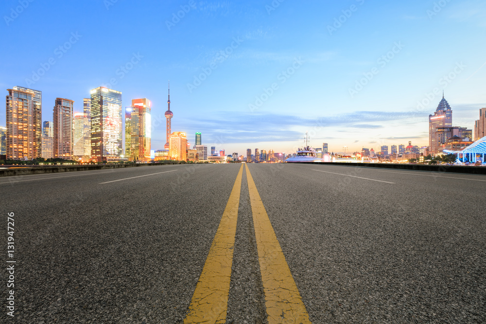 Asphalt road and modern cityscape at dusk in Shanghai