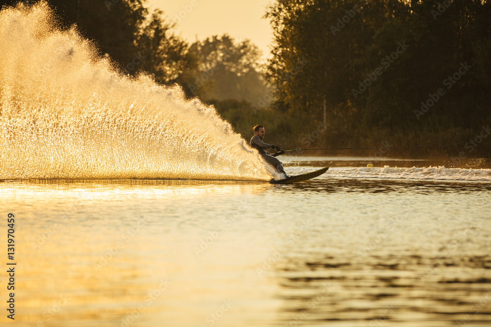 Man riding wakeboard on lake with splashes