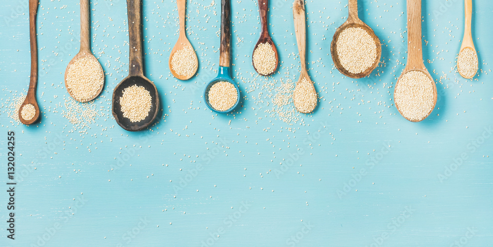 Quinoa seeds in different spoons over light blue background, top view, copy space, horizontal compos