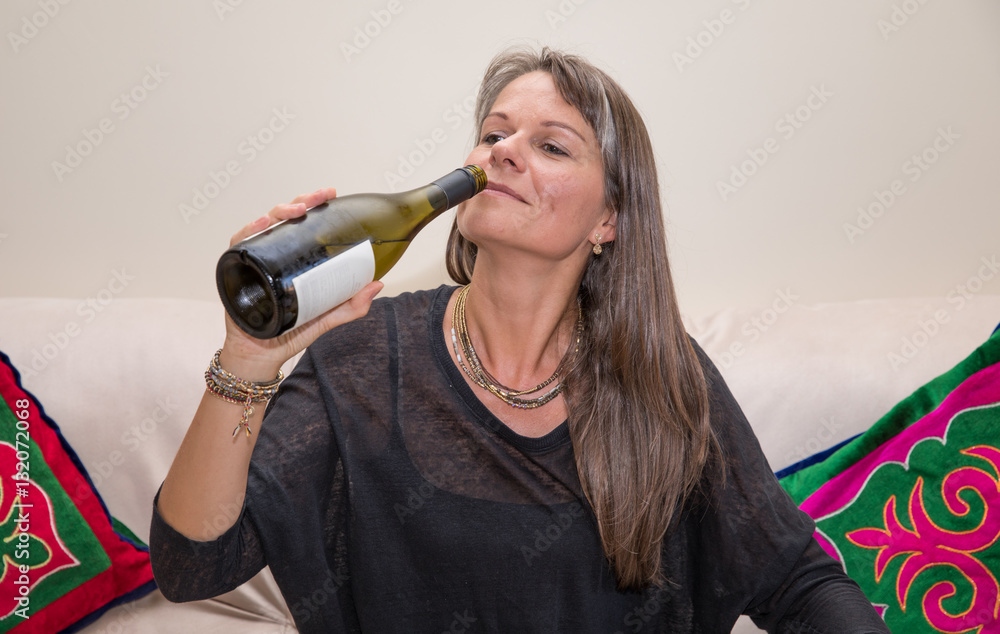 Middle aged woman on a couch with a glass of white wine.