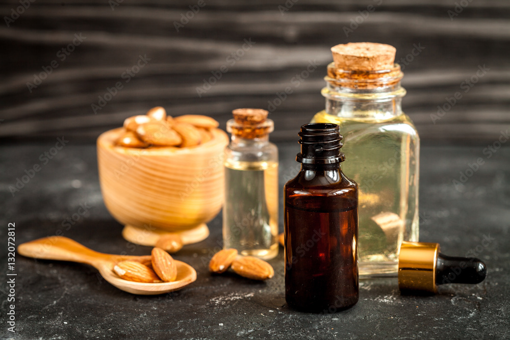 cosmetic almond oil in glass bottle on dark wooden background