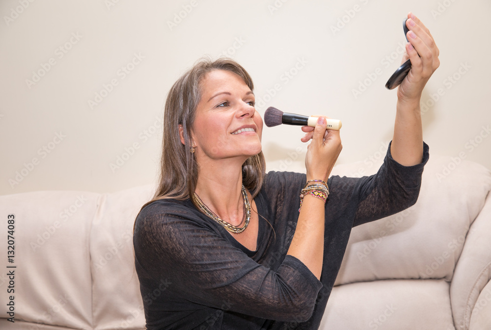 Middle aged woman applying make-up.