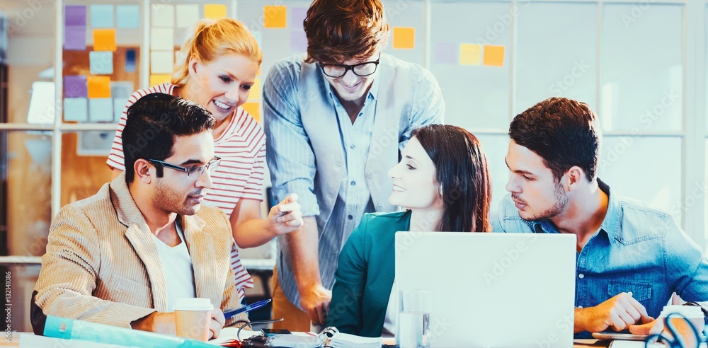 Happy creative business team using laptop in meeting