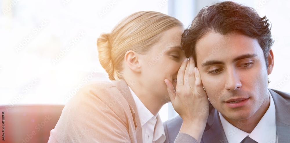 Businesswoman whispering something to her colleague