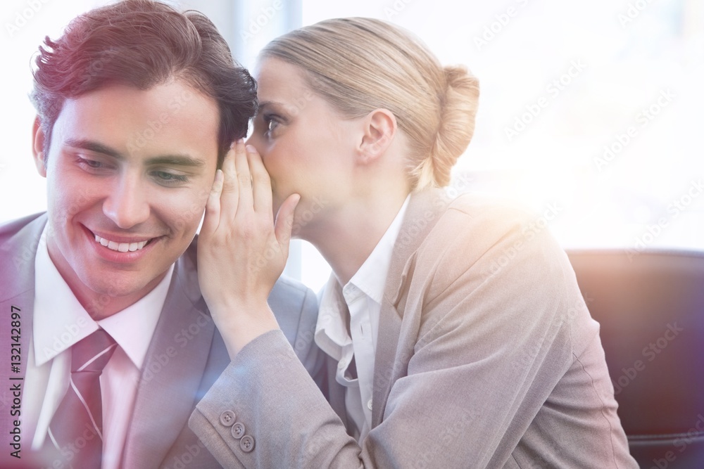 Young businesswoman whispering something to her colleague