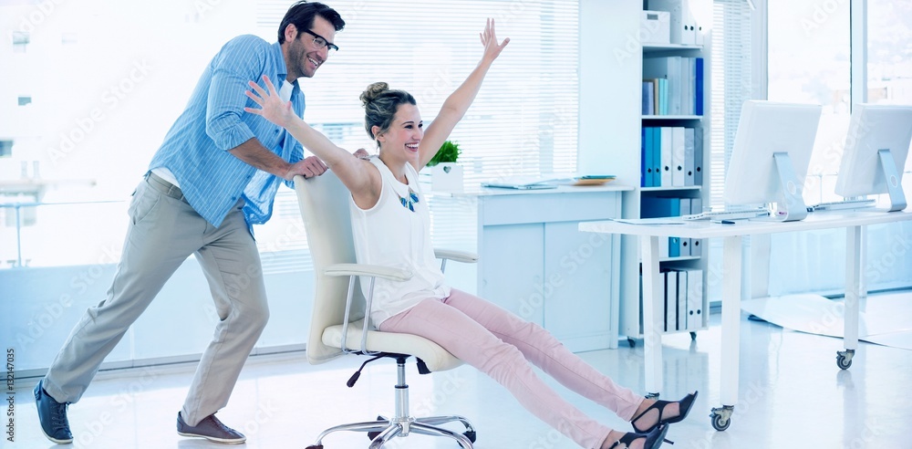 Smiling photo editors having fun with on a swivel chair