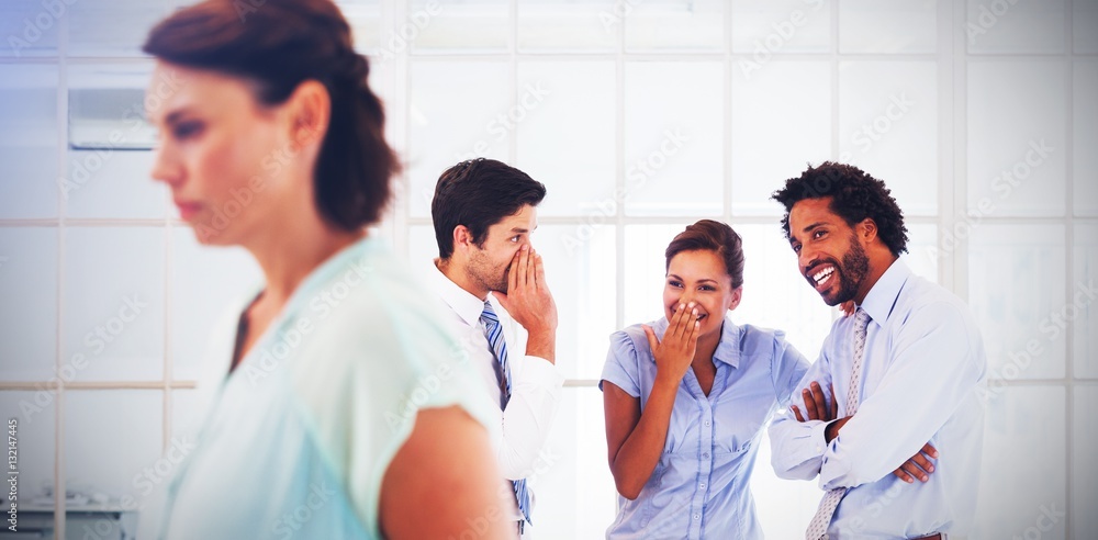 Colleagues gossiping with sad businesswoman in foreground