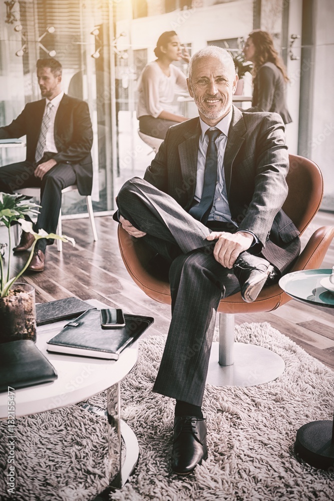 Smiling businessman sitting on chair in office