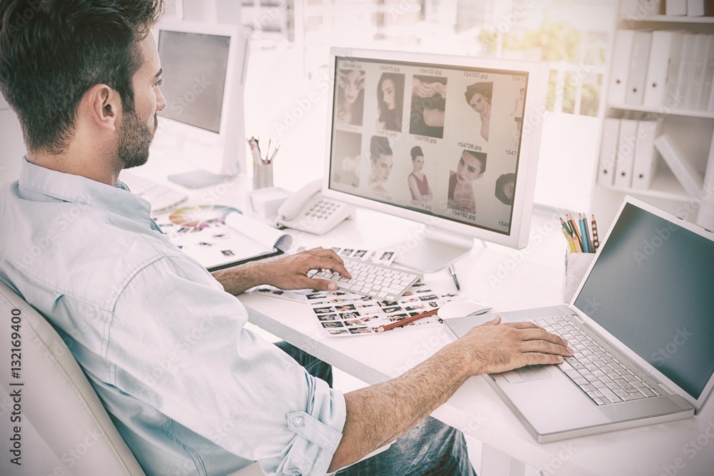 Male photo editor working on computer in a bright office