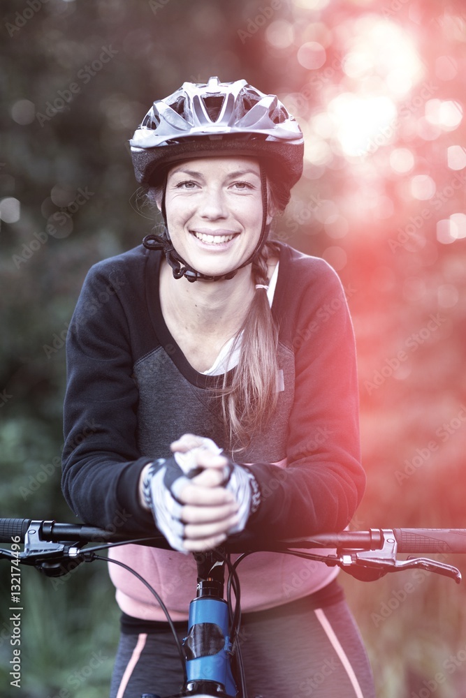 Portrait of female biker with mountain bike in countryside