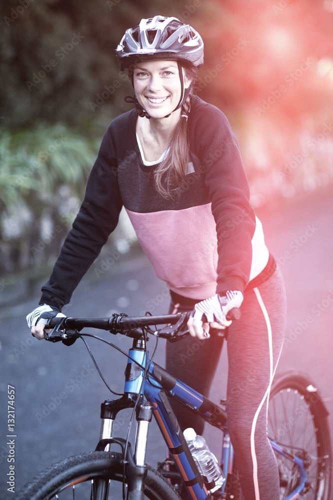 Portrait of female biker with mountain bike in countryside