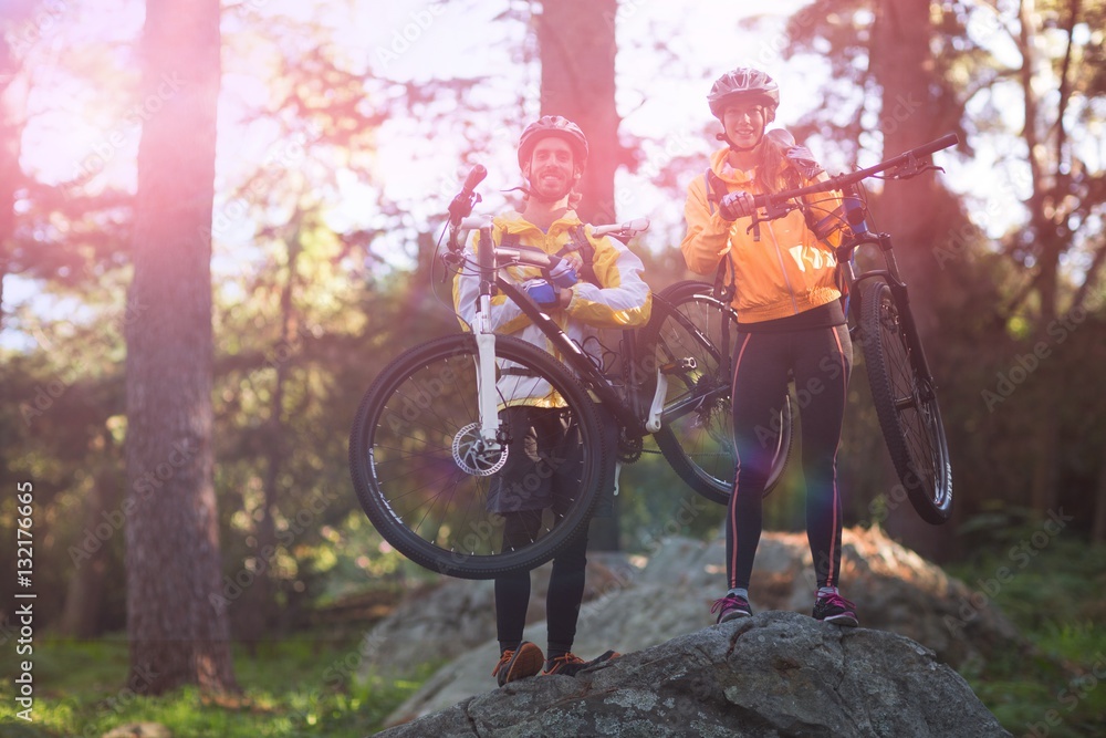 Portrait of biker couple carrying mountain bike