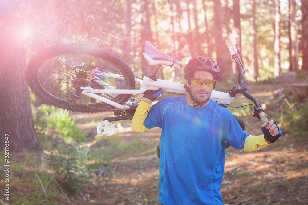 Male mountain biker carrying bicycle while walking