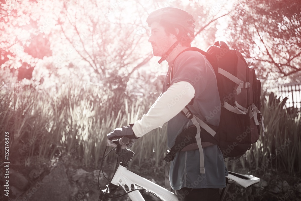 Side view of male mountain biker with bicycle in forest