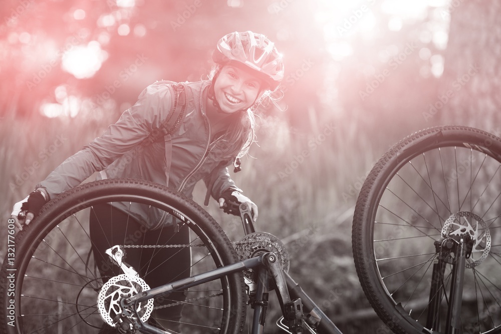 Portrait of female biker repairing mountain bike