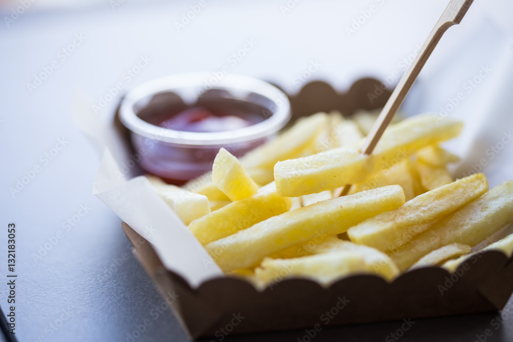 French fried potatoes in metal basket on wooden background