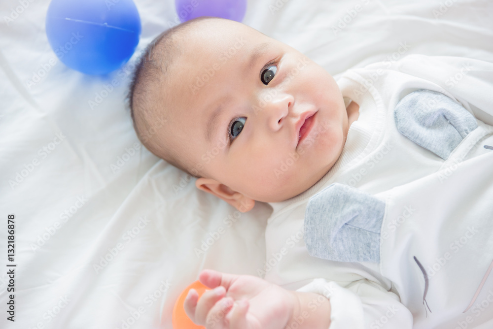 Little asian child lying on bed with ball