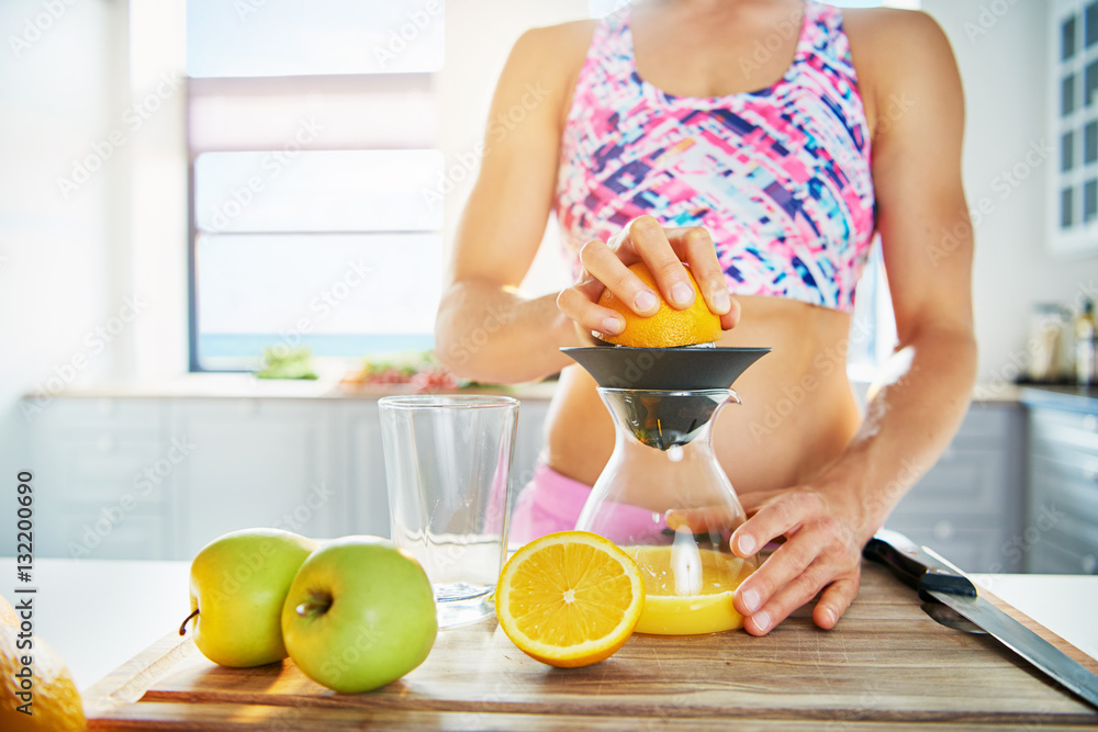 Sportive woman pressing orange juice with squeezer