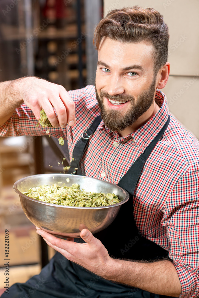 Brewer with green hops dressed in apron and checkered shirt at the manufacturing. Epertising quality