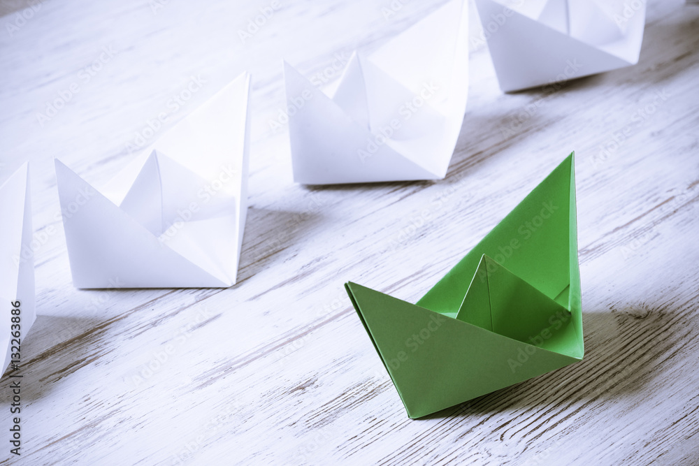 Business leadership concept with white and color paper boats on 