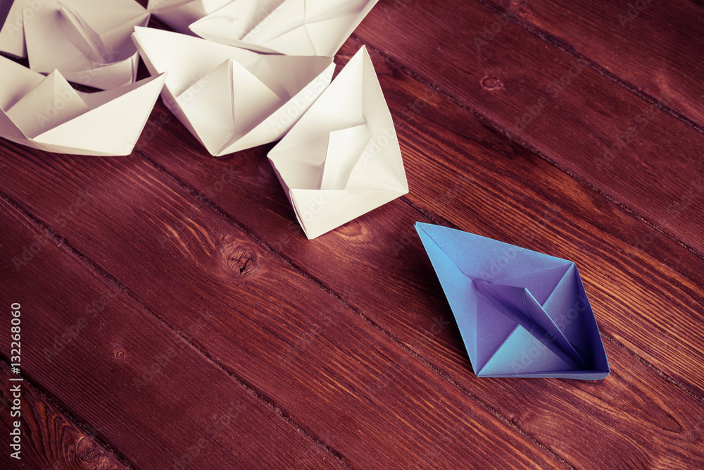 Business leadership concept with white and color paper boats on 