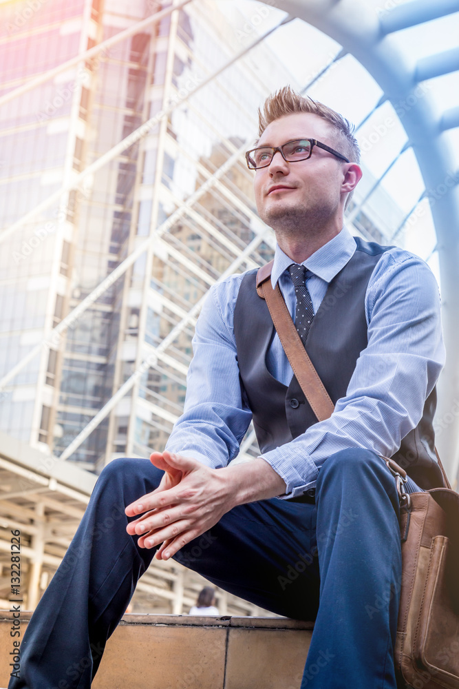 smart handsome american Businessman sitiing outside office building urban background