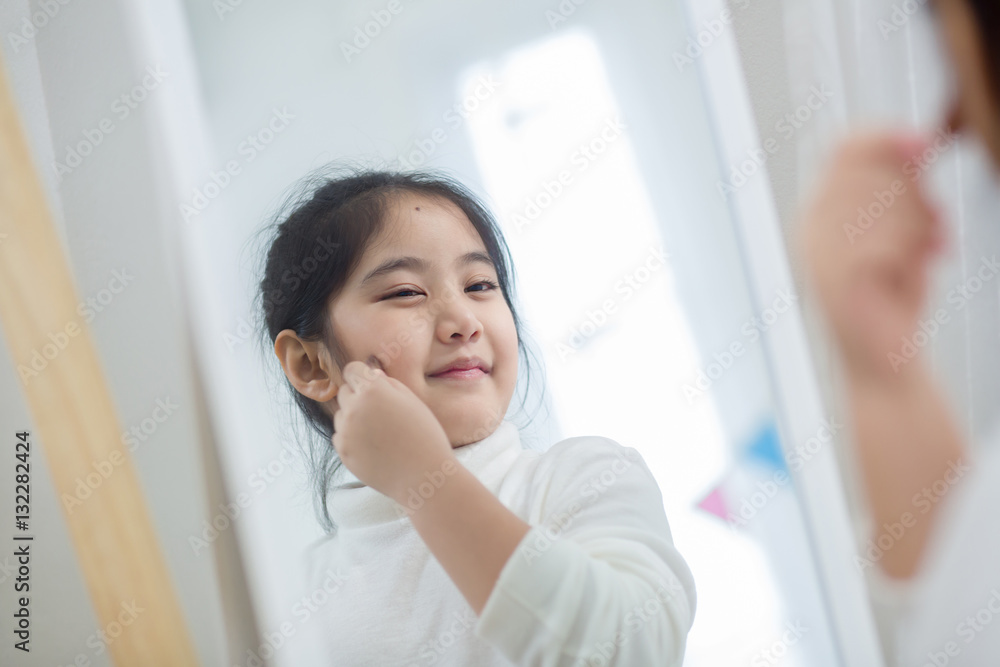 Pretty Asian child doing make up front of the mirror