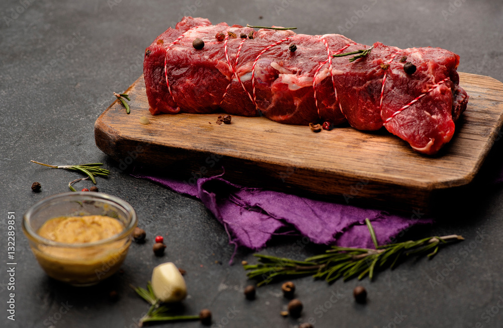 Raw meat with spices, mustard and rosemary on wooden board. Fresh beef. Roast . Ready to roasting. T