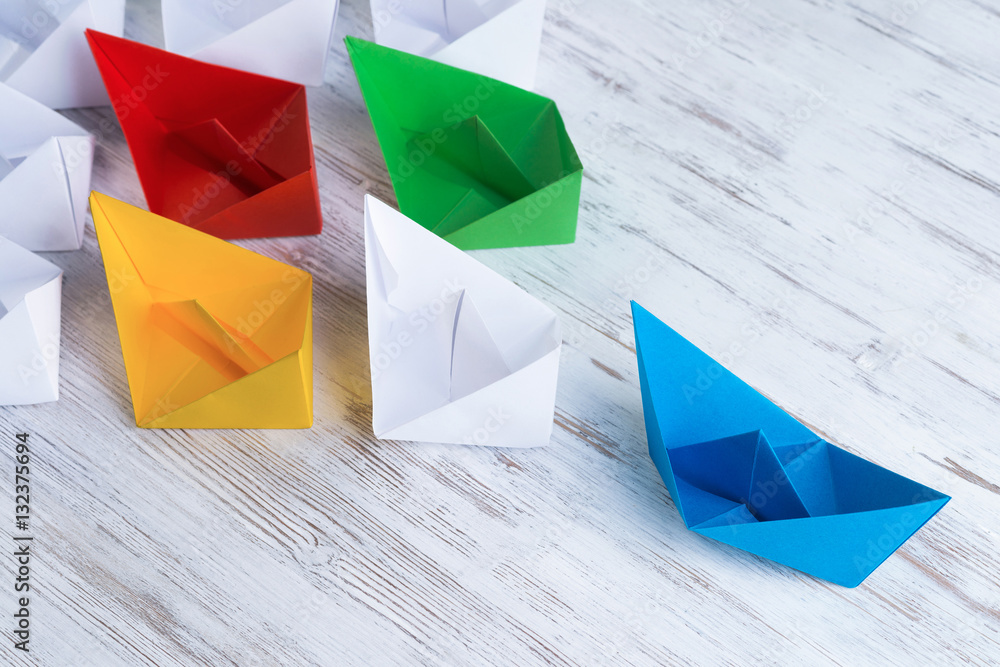 Business leadership concept with white and color paper boats on 