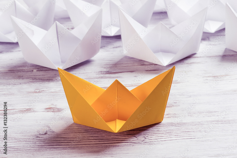 Business leadership concept with white and color paper boats on 