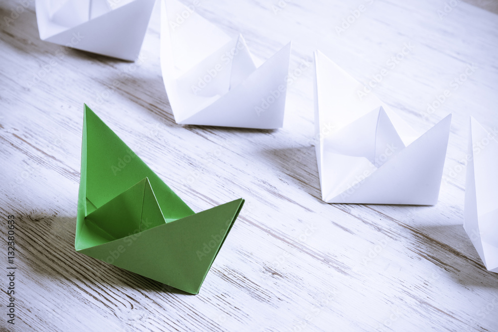 Business leadership concept with white and color paper boats on 