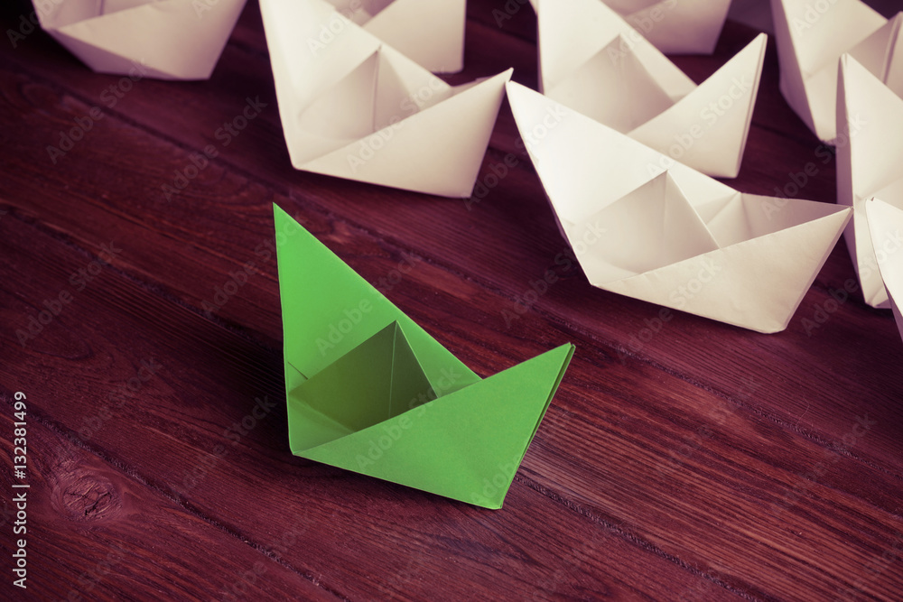 Business leadership concept with white and color paper boats on 