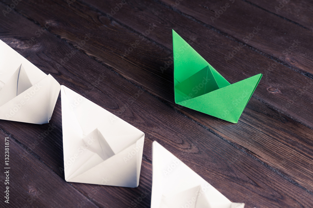 Business leadership concept with white and color paper boats on 