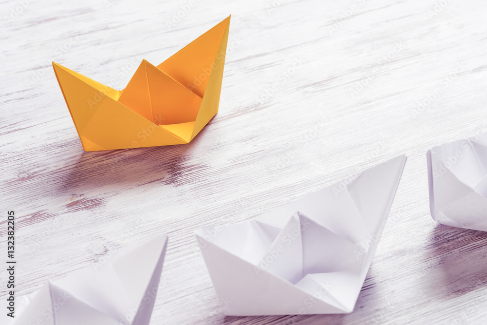 Business leadership concept with white and color paper boats on 