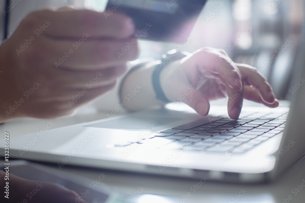 Young man holding credit card and using laptop computer. Online shopping concept,close up and select