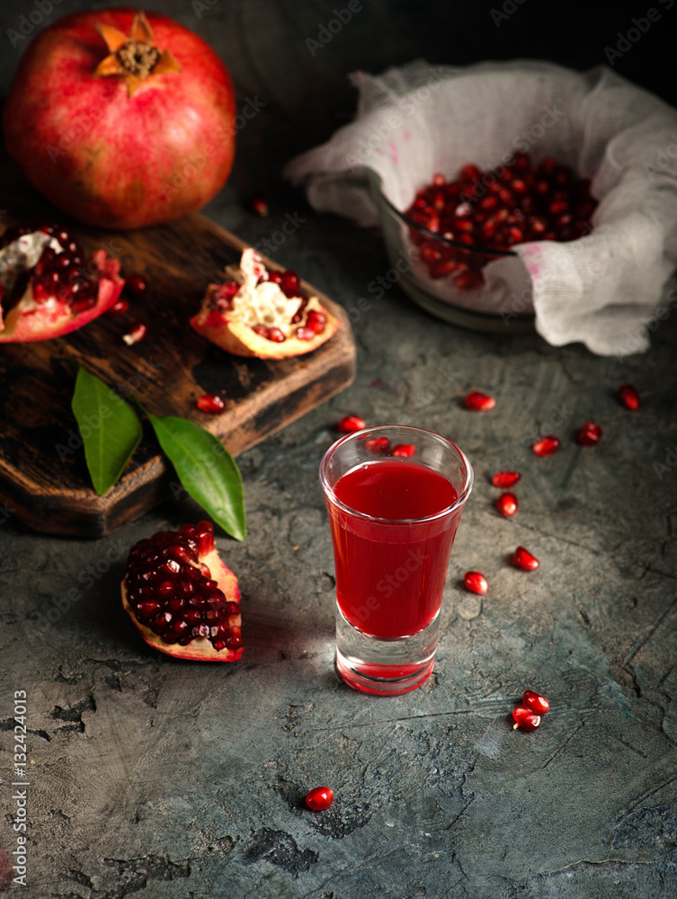 Glass of pomegranate juice. fruits with grains and leaves on the table. Make . Dark moody.