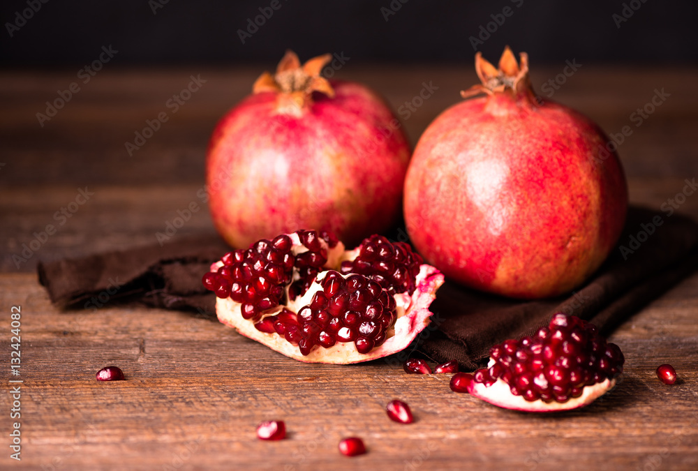 Pomegranate fruits with grains on wooden table.