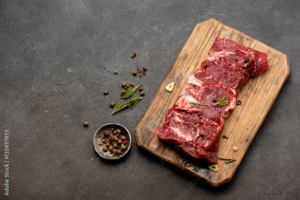 木板上的生肉配香料和迷迭香。新鲜牛肉。准备烤。俯视图。