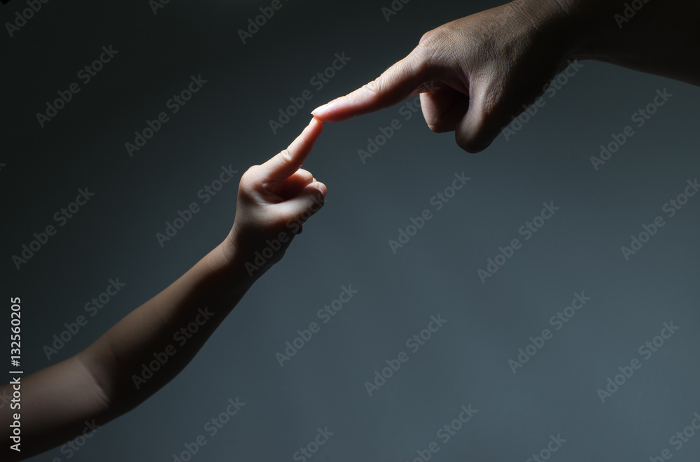 two hands, father and kid, touch each other as symbol of family love and trust on black background