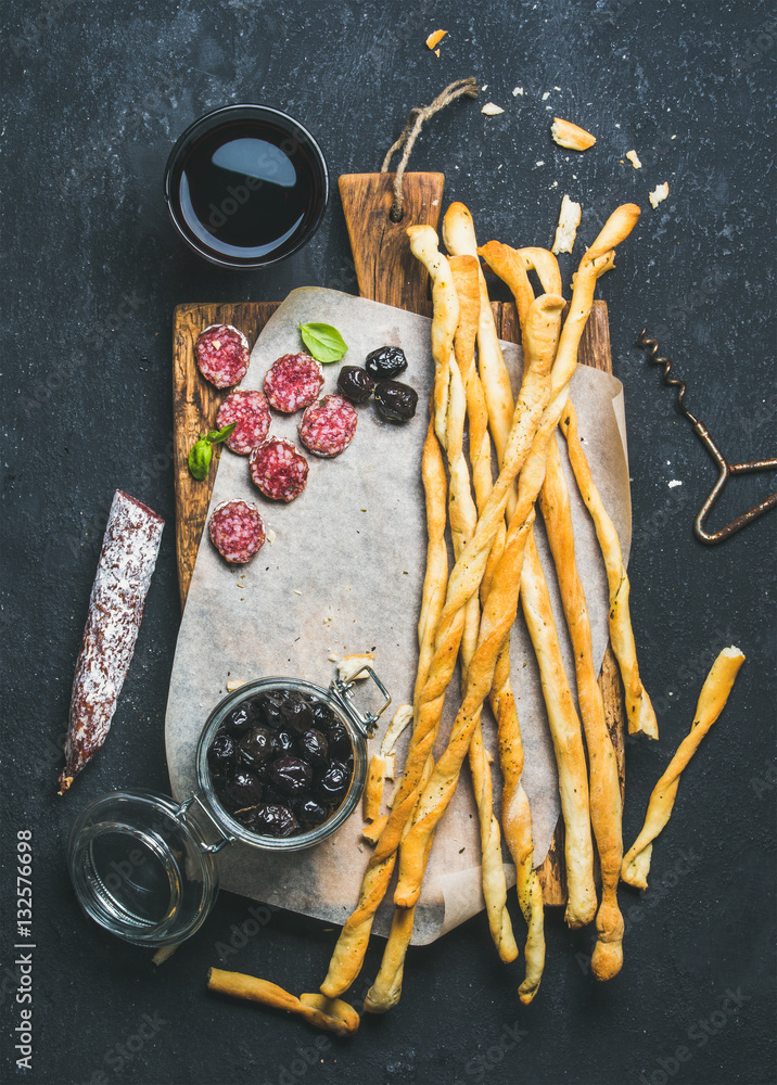 Wine and appetizers set. Italian Grissini bread sticks, dry cured pork meat sausage, black olives in