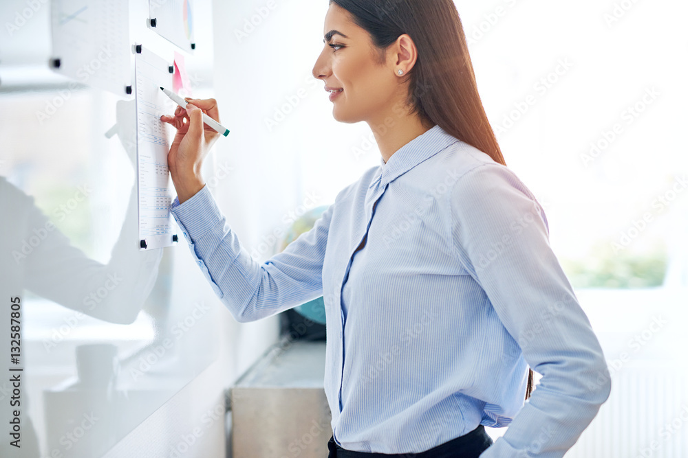 Young businesswoman writing notes on a notice