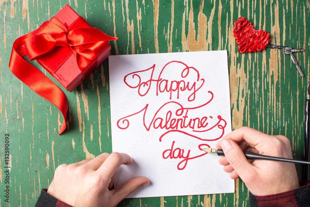 Man writing a Valentines day card and preparing present