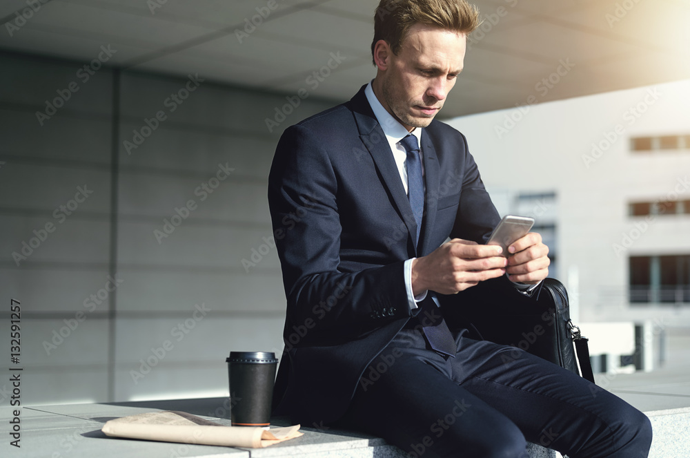 Young stylish businessman while using his phone