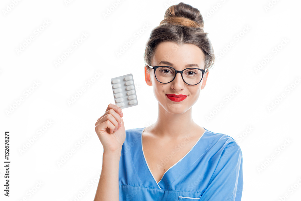 Young female doctor in uniform holding pills. Studio shot on the white background