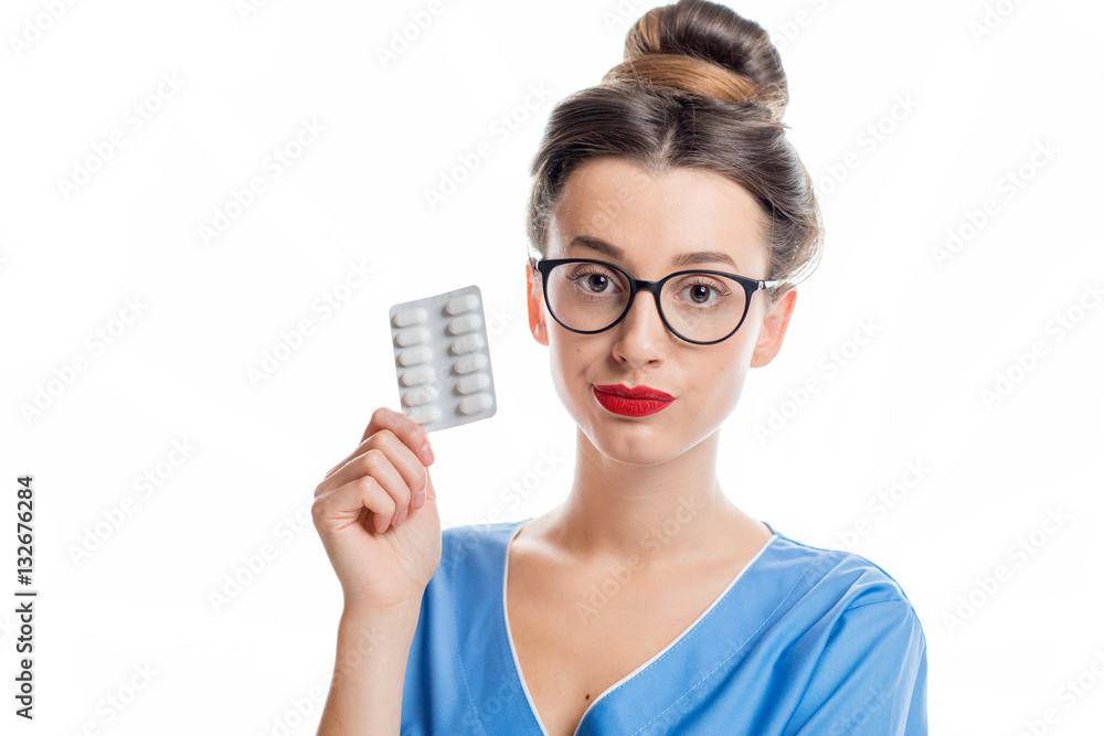 Young female doctor in uniform holding pills. Studio shot on the white background