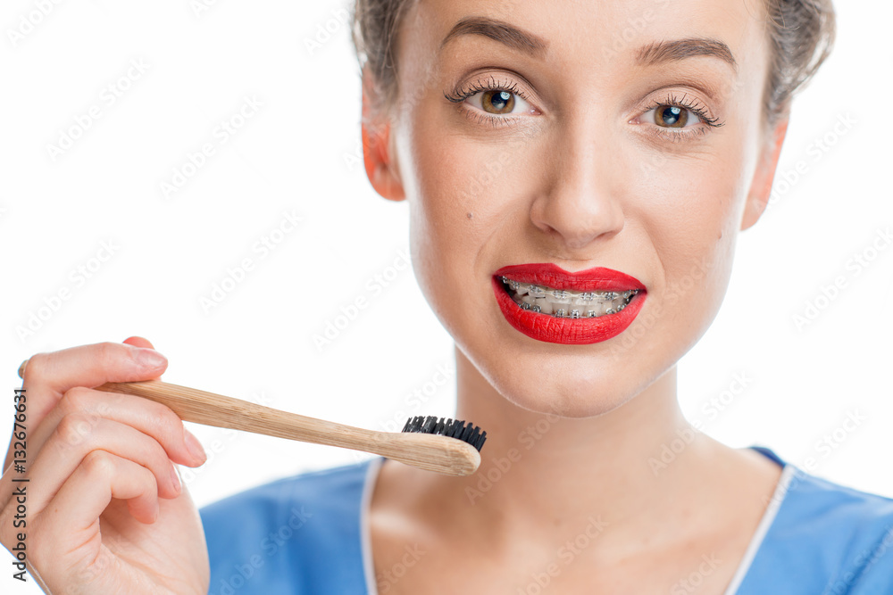 Portrait of confused woman with tooth braces holding a toothbrush on the white background. Woman wor