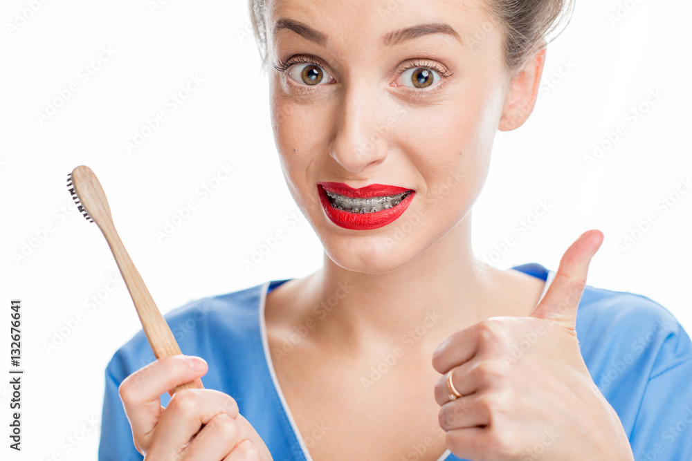 Portrait of confused woman with tooth braces holding a toothbrush on the white background. Woman wor